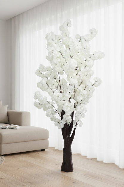 White artificial tree in a living room setting with a sofa and curtains.